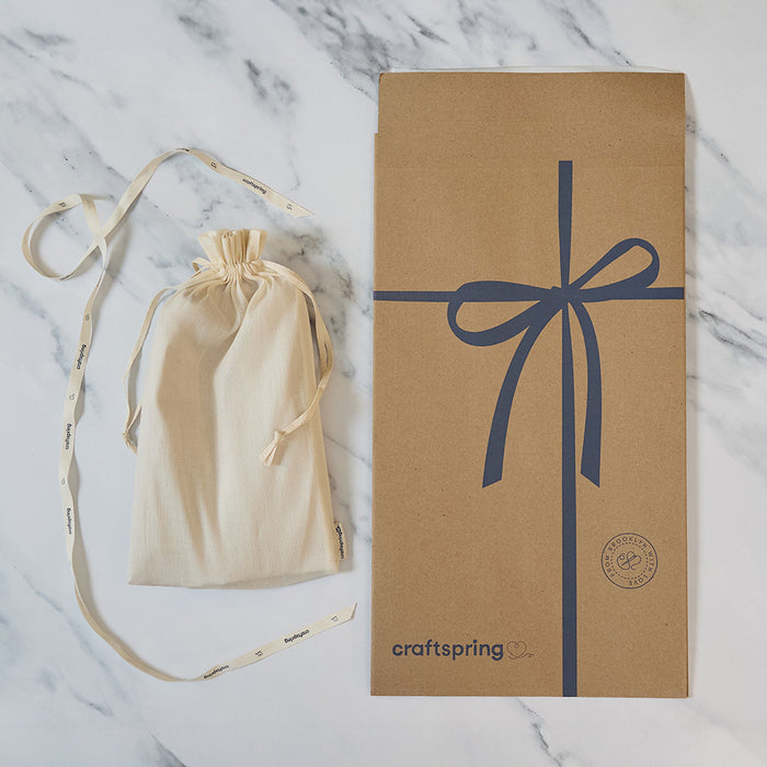 Craftspring packaging for Praying Angel Tree Topper - Light, featuring a branded mailer and protective cloth bag displayed on a marble surface — ready to safely deliver heirloom-quality, ethically crafted felt holiday decor from artisans using sustainable wool.