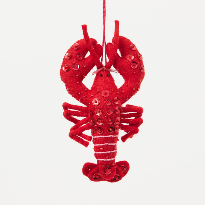 Commemorate the bounty of the northeastern seaboard with our handcrafted Bejeweled Red Lobster Ornament, designed to bring the spirit of coastal Maine to your home. Crafted from vibrant red felt and embellished with sparkling beads and sequins, this festive lobster ornament catches the light beautifully, adding texture, shimmer, and whimsical seaside charm to your holiday décor.