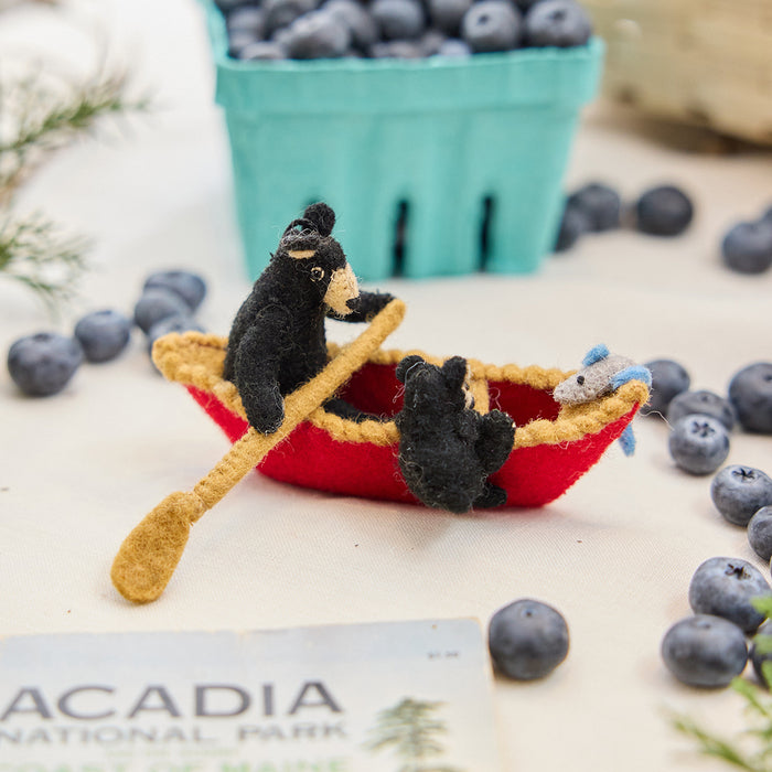 Craftspring’s handmade felt Bears in a Canoe ornament — a mama bear paddling a canoe with a cub climbing over the side, displayed with evergreens and blueberries for a whimsical holiday scene, perfect for Christmas decorating or gifting, ethically crafted by artisans using sustainable wool.