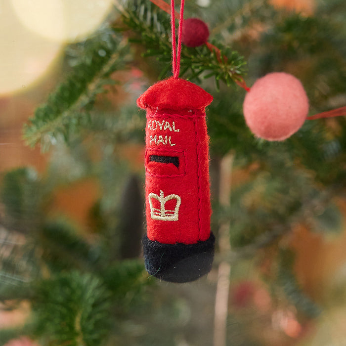 Craftspring’s British Post Box ornament — featuring gold embroidered details, displayed on a Christmas tree for a festive holiday scene, ethically crafted by artisans using sustainable wool.