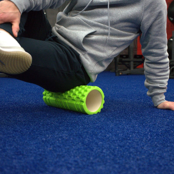 Gronk Fitness green foam roller in use on blue carpet