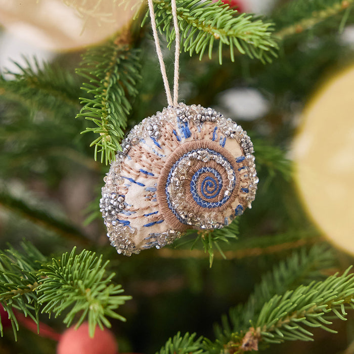 Craftspring’s Moon Snail Shell Ornament displayed on a Christmas tree — made of satin with intricate beaded and embroidered details, adding coastal holiday charm and gifting warmth, ethically crafted by artisans.