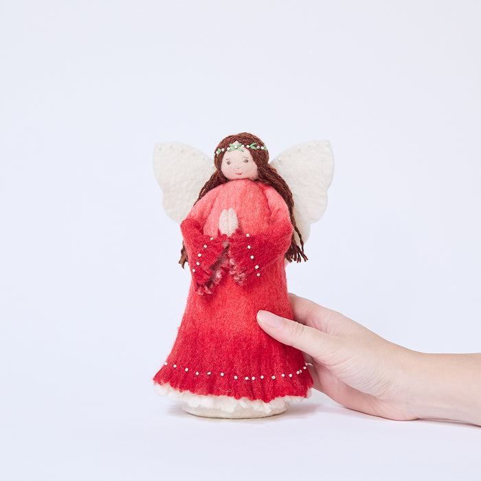 Craftspring’s Praying Angel Tree Topper - Light held in hand to show its size — felt angel in a red dress with white beads, embroidered and beaded wreath crown, and hands in prayer, a charming heirloom-quality piece for holiday gifting — ethically crafted by artisans using sustainable wool.