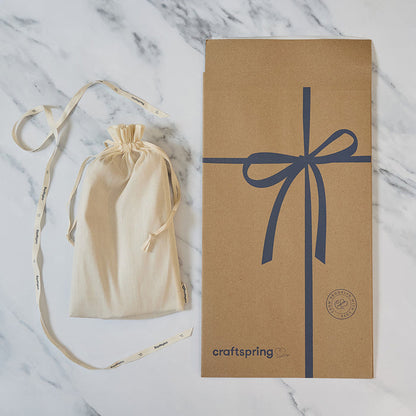 Craftspring packaging for Praying Angel Tree Topper - Light, featuring a branded mailer and protective cloth bag displayed on a marble surface — ready to safely deliver heirloom-quality, ethically crafted felt holiday decor from artisans using sustainable wool.