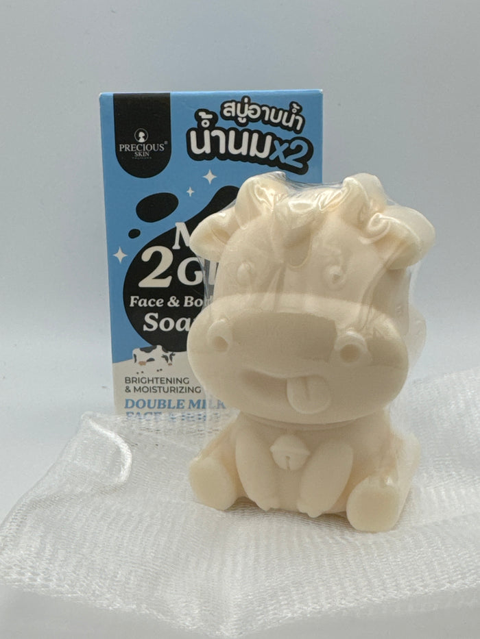 Soap and box: Cow-shaped Milk 2 Glow soap bar in clear wrapping with a foaming net and product box.