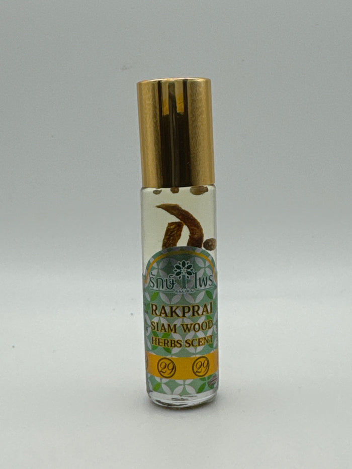 Bottle photo: Rakprai Siam Wood Herbs Scent massage oil in a clear bottle with a gold cap and visible botanical pieces.