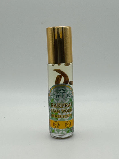 Bottle photo: Rakprai Siam Wood Herbs Scent massage oil in a clear bottle with a gold cap and visible botanical pieces.